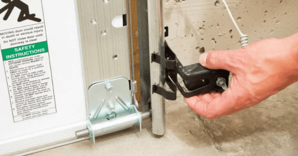 Hand adjusts garage door safety sensor light.